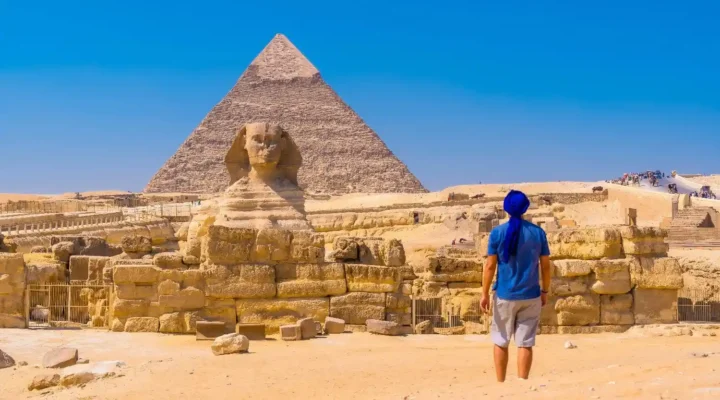 man in blue shirt walking towards the great sphinx and the Pyramids of Egypt the best place for dental tourism
