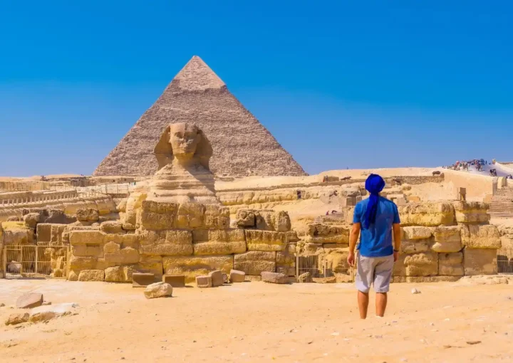 man in blue shirt walking towards the great sphinx and the Pyramids of Egypt the best place for dental tourism