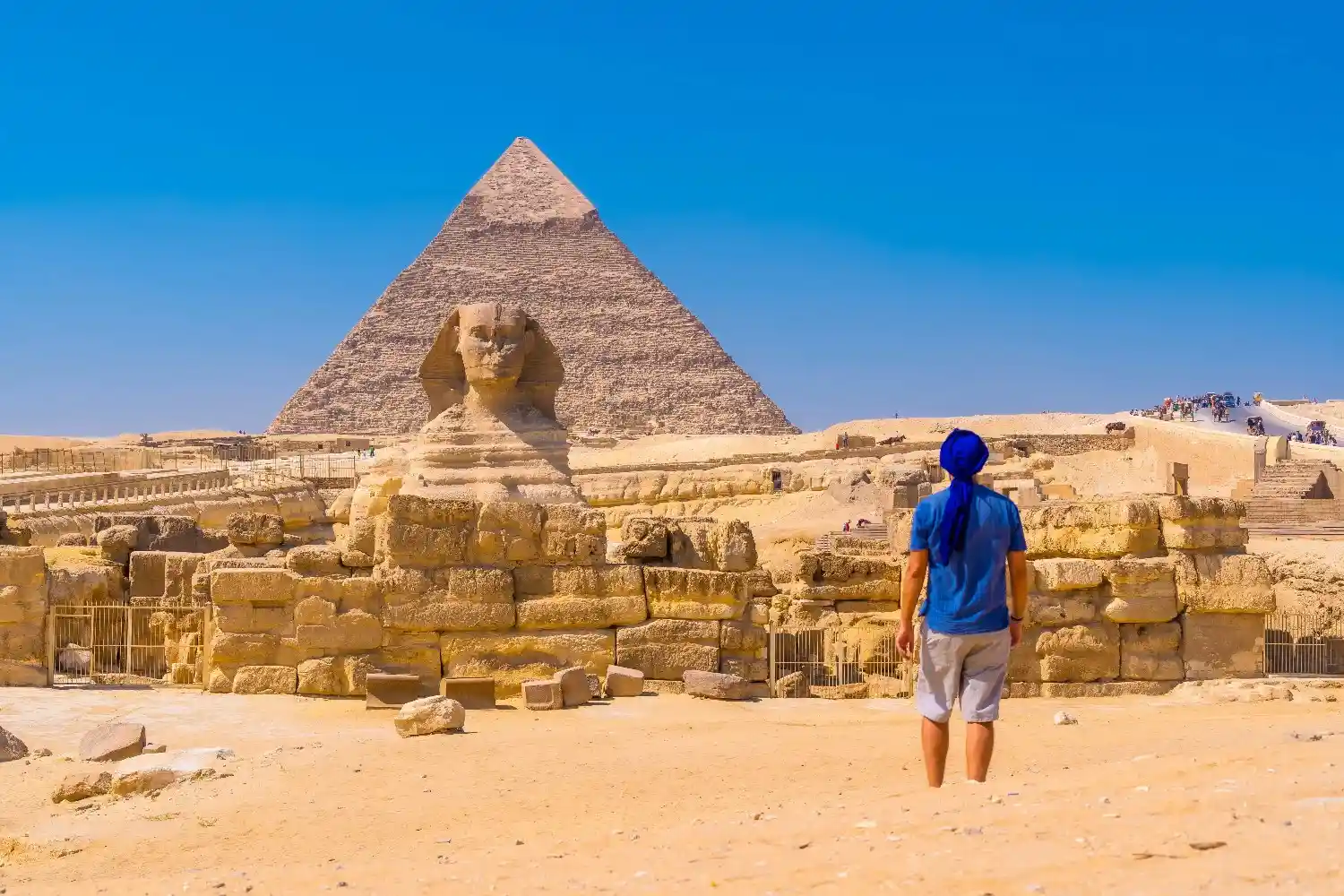 man in blue shirt walking towards the great sphinx and the Pyramids of Egypt the best place for dental tourism